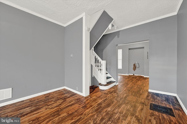 entrance foyer with crown molding, a textured ceiling, and dark hardwood / wood-style flooring