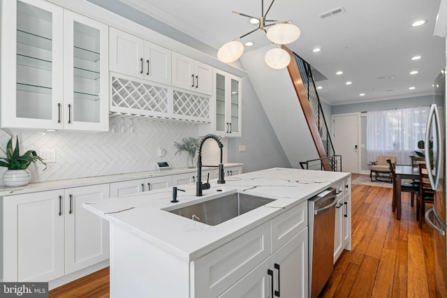 kitchen featuring backsplash, white cabinetry, a kitchen island with sink, wood-type flooring, and sink