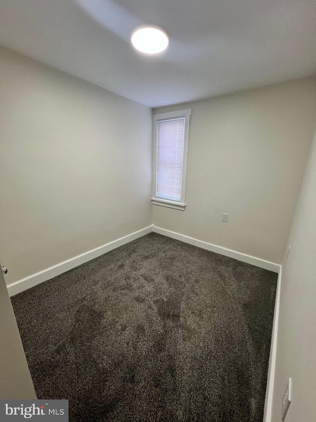 unfurnished room with dark carpet