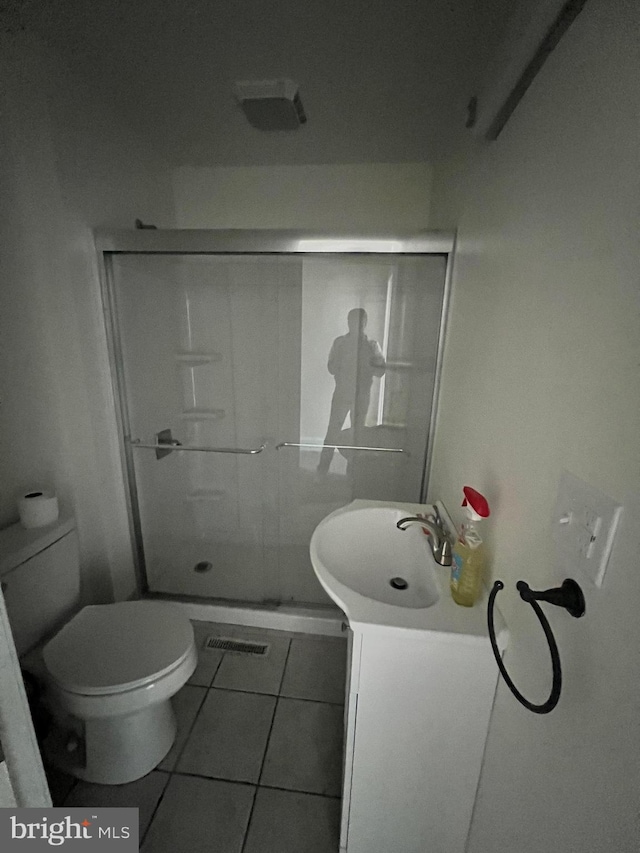 bathroom with vanity, a shower with shower door, toilet, and tile patterned floors