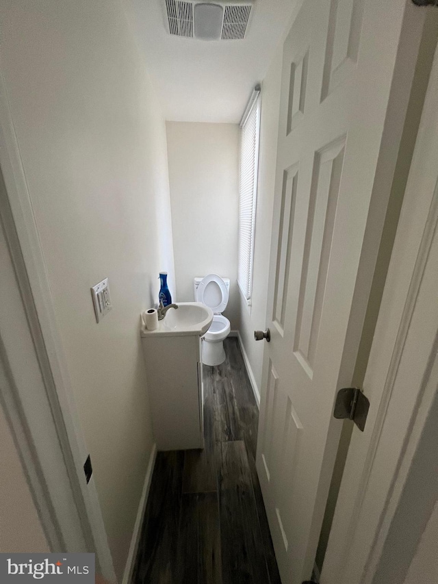 bathroom with toilet, hardwood / wood-style floors, and vanity