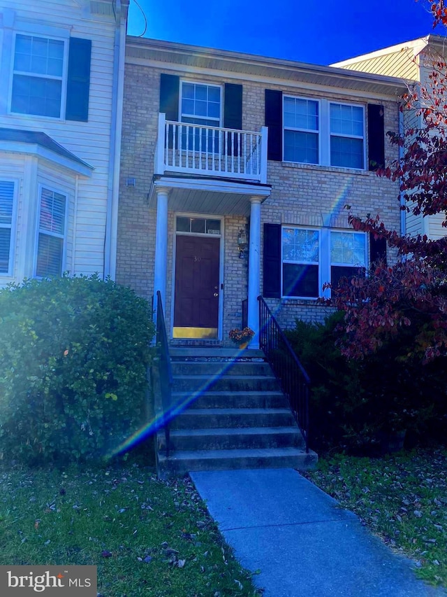 view of property featuring a balcony and brick siding