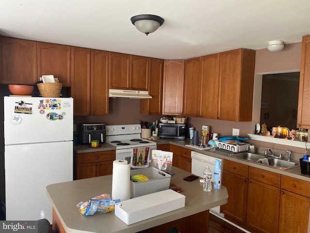 kitchen featuring a sink, brown cabinetry, white appliances, under cabinet range hood, and a center island