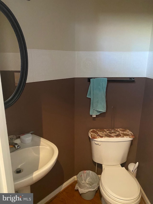 half bath with toilet, baseboards, and a sink