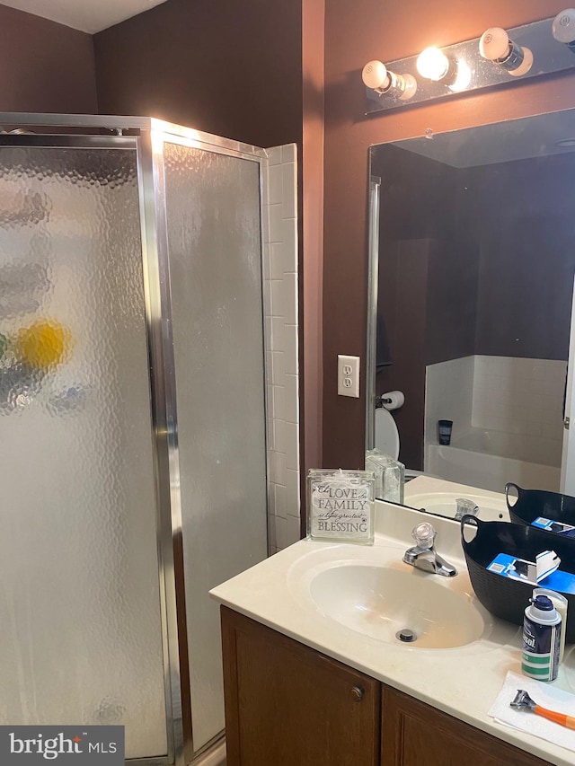 bathroom featuring a shower with door and vanity