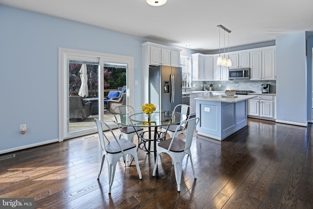 kitchen with pendant lighting, a kitchen island, white cabinets, and stainless steel appliances