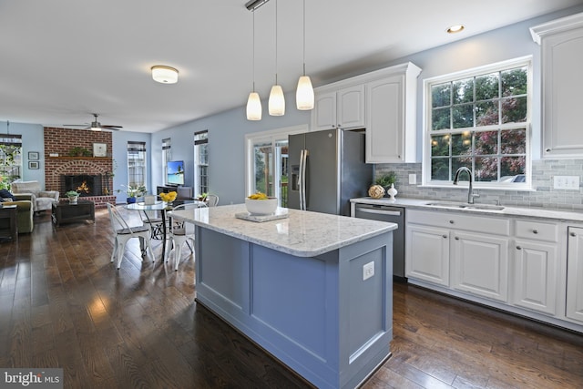 kitchen featuring plenty of natural light, white cabinets, sink, decorative light fixtures, and stainless steel appliances