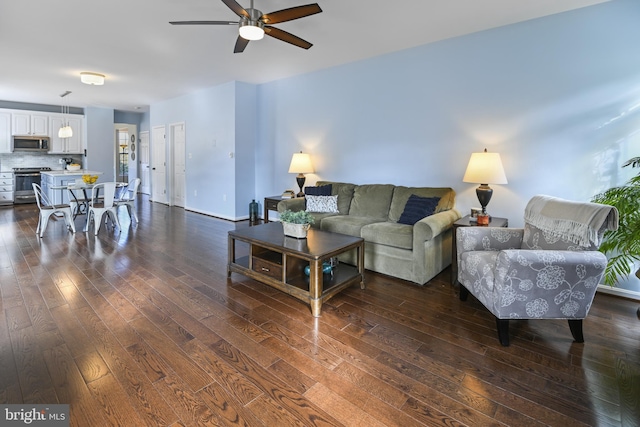 living room with ceiling fan and dark wood-type flooring