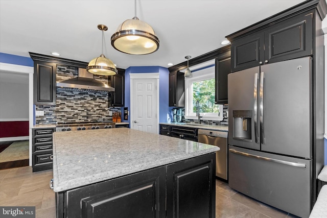 kitchen with hanging light fixtures, backsplash, appliances with stainless steel finishes, wall chimney exhaust hood, and a center island