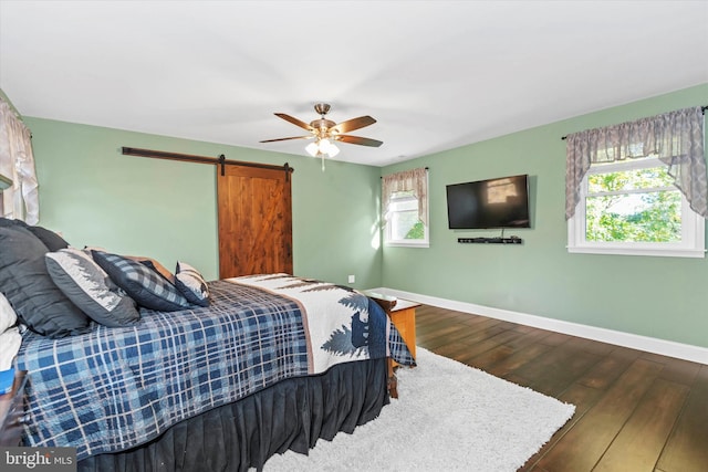 bedroom with ceiling fan, hardwood / wood-style flooring, and a barn door