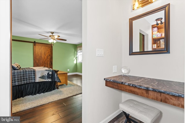 interior space featuring ceiling fan, wood-type flooring, and a barn door