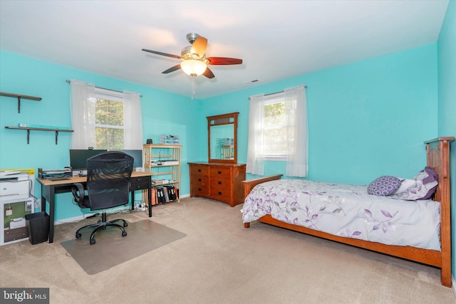 bedroom featuring ceiling fan, multiple windows, and light colored carpet