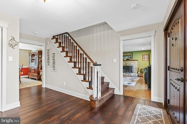 entrance foyer with a stone fireplace and dark hardwood / wood-style flooring