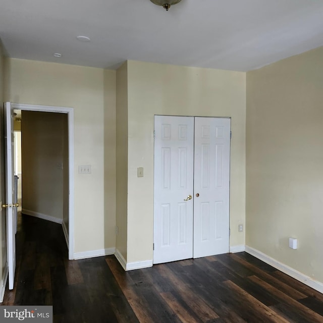 unfurnished bedroom with dark wood-type flooring and a closet