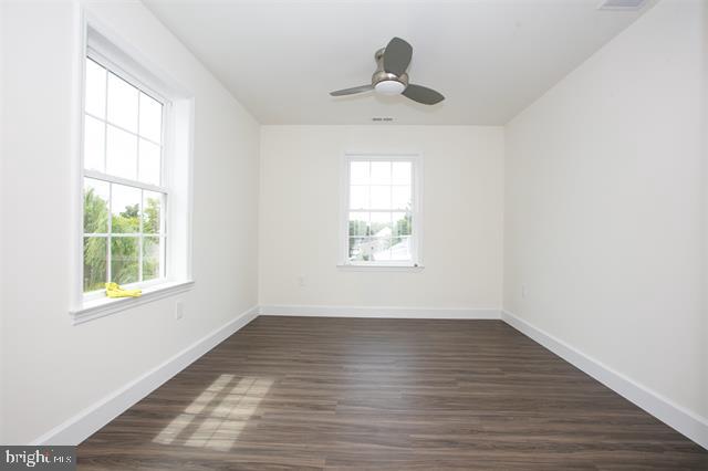 unfurnished room with dark wood-type flooring, plenty of natural light, and ceiling fan