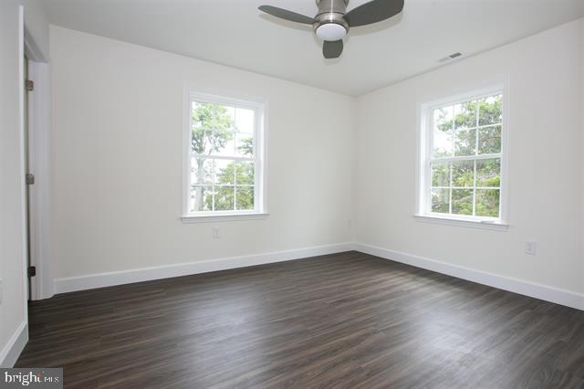 empty room with dark hardwood / wood-style floors, ceiling fan, and a wealth of natural light