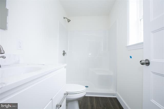 bathroom with vanity, hardwood / wood-style flooring, toilet, and a shower