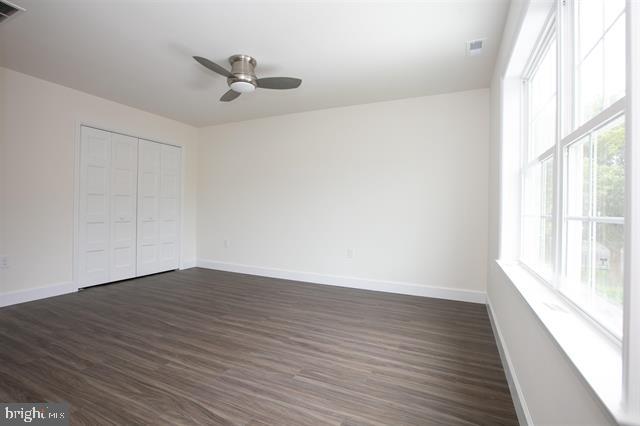 unfurnished bedroom featuring a closet, ceiling fan, and dark hardwood / wood-style flooring