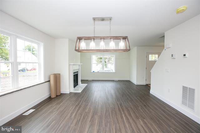 unfurnished living room featuring a healthy amount of sunlight and dark hardwood / wood-style floors