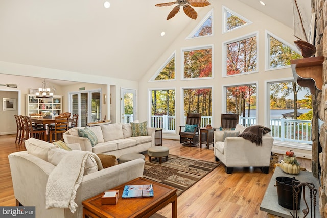 sunroom / solarium featuring a water view, vaulted ceiling, plenty of natural light, and ceiling fan with notable chandelier