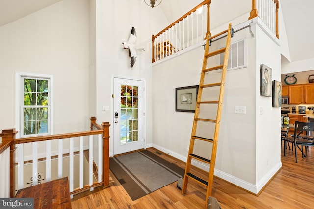 entryway with high vaulted ceiling and light hardwood / wood-style flooring