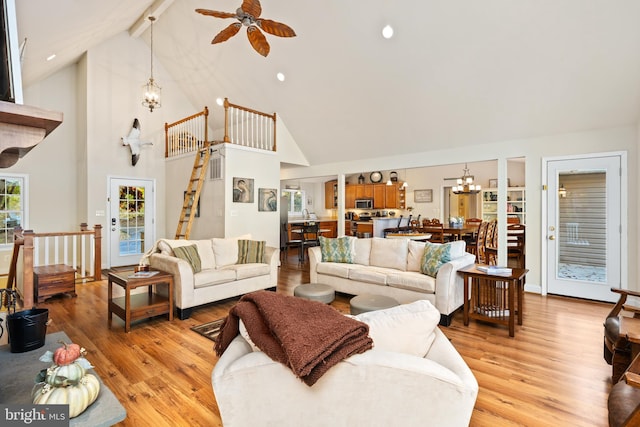 living room featuring beamed ceiling, ceiling fan with notable chandelier, light wood-type flooring, and high vaulted ceiling