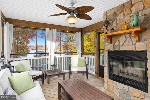 sunroom / solarium featuring a wealth of natural light, a water view, a fireplace, and ceiling fan