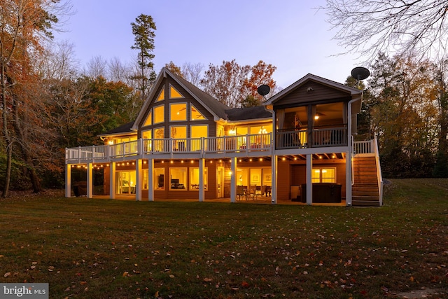 back house at dusk featuring a wooden deck, a yard, and a patio