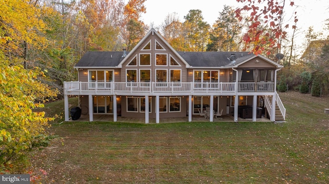 rear view of property with a wooden deck, a yard, a patio, and a sunroom