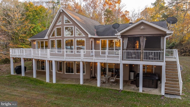 rear view of property featuring a wooden deck, a yard, a patio area, and a sunroom