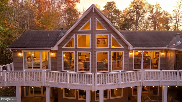 back house at dusk featuring a deck