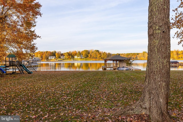 dock area with a playground, a lawn, and a water view