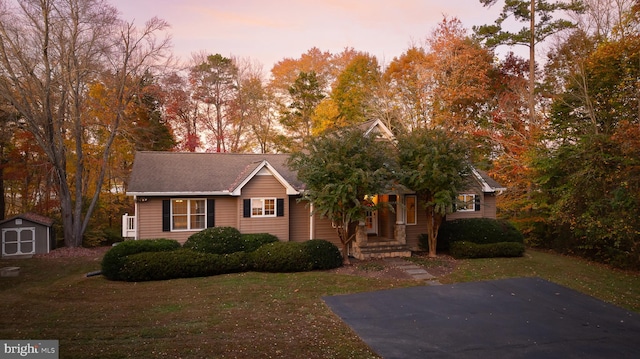 view of front of house featuring a storage shed and a lawn