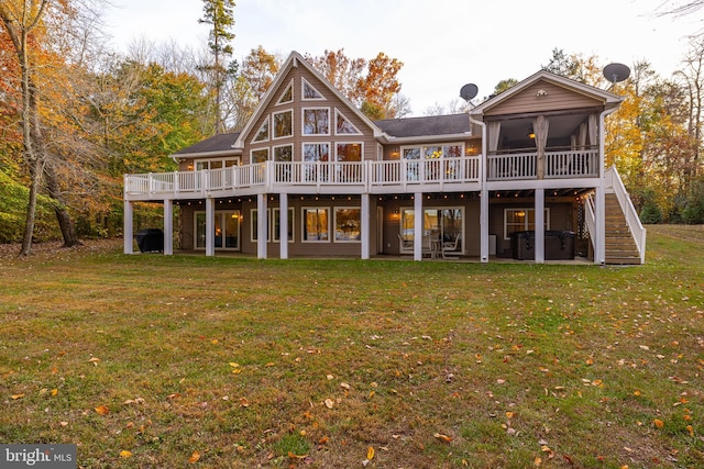 back of property featuring a wooden deck, a lawn, and a sunroom