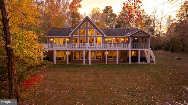 back house at dusk with a sunroom, a lawn, and a patio area