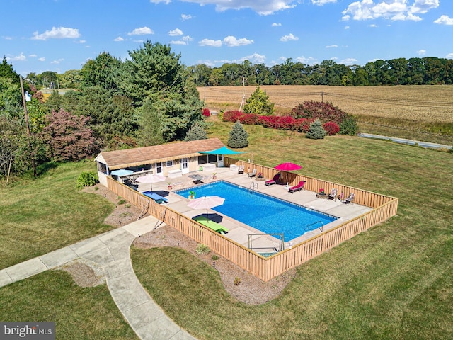 view of swimming pool featuring a patio, a lawn, and a rural view