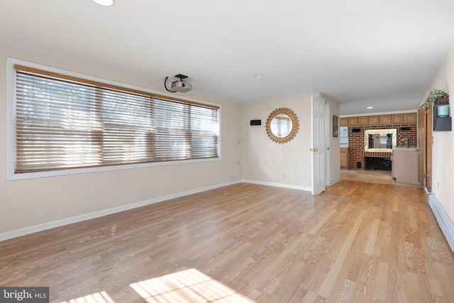 unfurnished living room featuring light hardwood / wood-style flooring and a brick fireplace