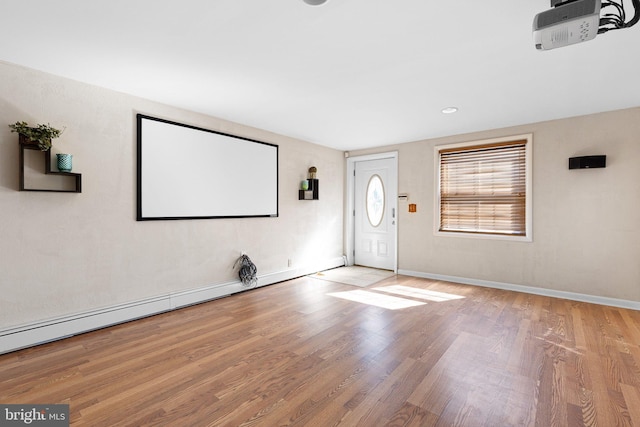 home theater featuring a baseboard heating unit and light wood-type flooring