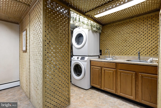 laundry area featuring baseboard heating, sink, and stacked washing maching and dryer