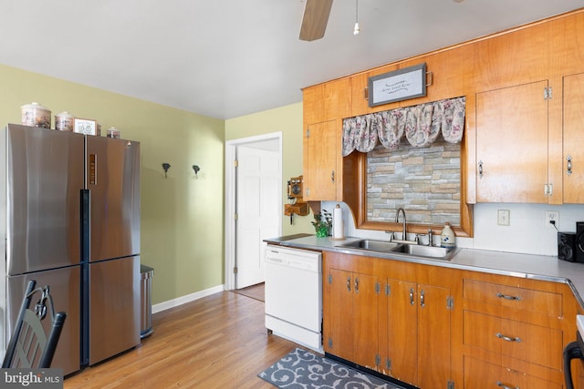 kitchen with sink, white dishwasher, ceiling fan, stainless steel refrigerator, and light hardwood / wood-style flooring