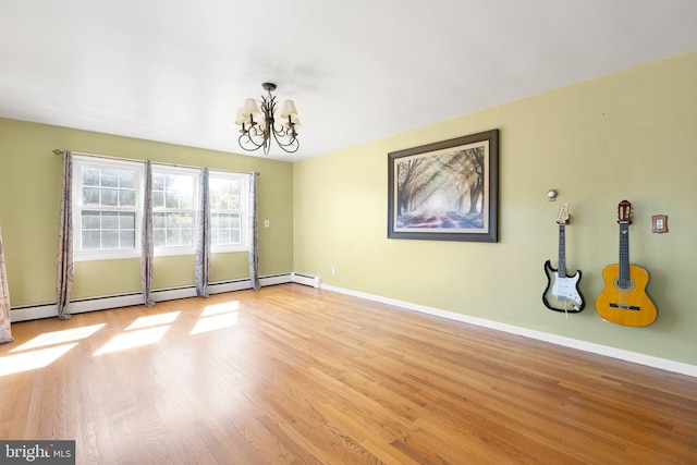 unfurnished room with baseboard heating, a chandelier, and light wood-type flooring