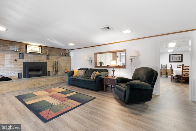 living room featuring ornamental molding, a brick fireplace, and wood-type flooring