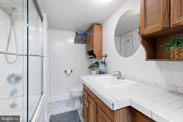 bathroom with vanity, toilet, crown molding, and a shower with shower door