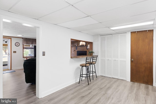 kitchen featuring a breakfast bar, a paneled ceiling, and light wood-type flooring