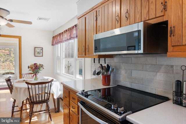 kitchen featuring decorative backsplash, electric range, light hardwood / wood-style flooring, and ceiling fan