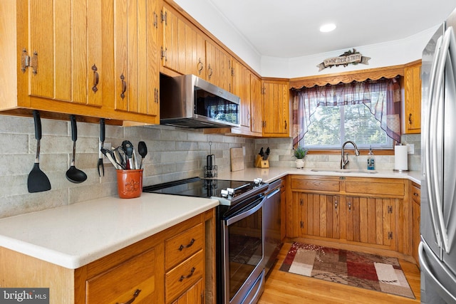 kitchen with tasteful backsplash, sink, light wood-type flooring, stainless steel appliances, and crown molding