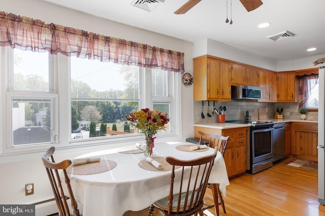 kitchen featuring ceiling fan, appliances with stainless steel finishes, light wood-type flooring, and decorative backsplash