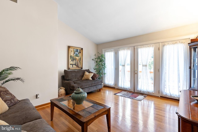 living room featuring french doors, light hardwood / wood-style floors, and high vaulted ceiling