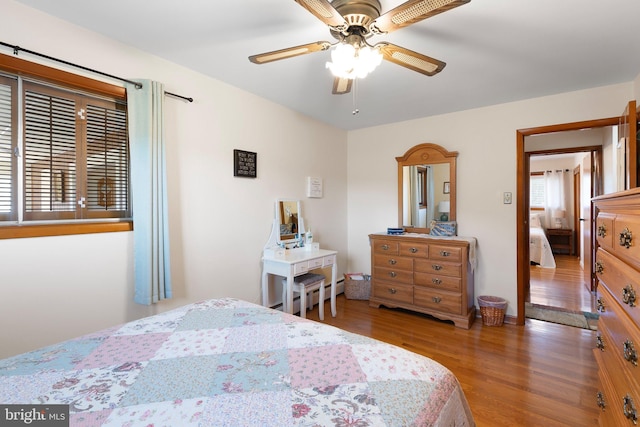 bedroom featuring ceiling fan, wood-type flooring, and multiple windows