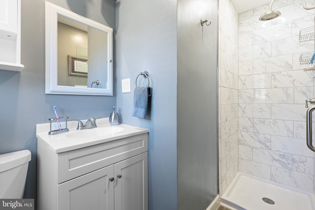 bathroom featuring vanity, toilet, and tiled shower